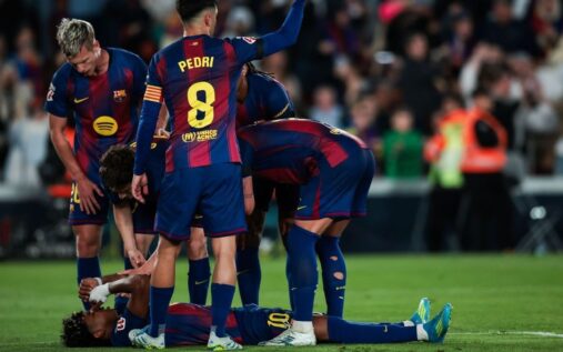 Lamine Yamal clutching his hamstring on the pitch while receiving medical attention at Camp Nou