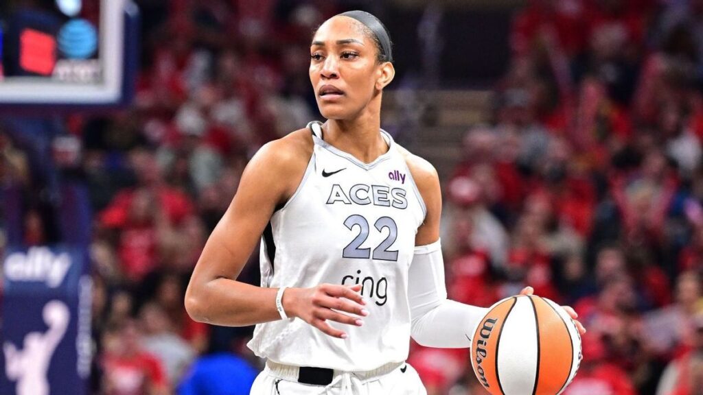 A'ja Wilson smiling in her Las Vegas Aces uniform on the basketball court
