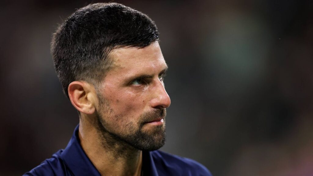 Novak Djokovic looking dejected on a clay tennis court