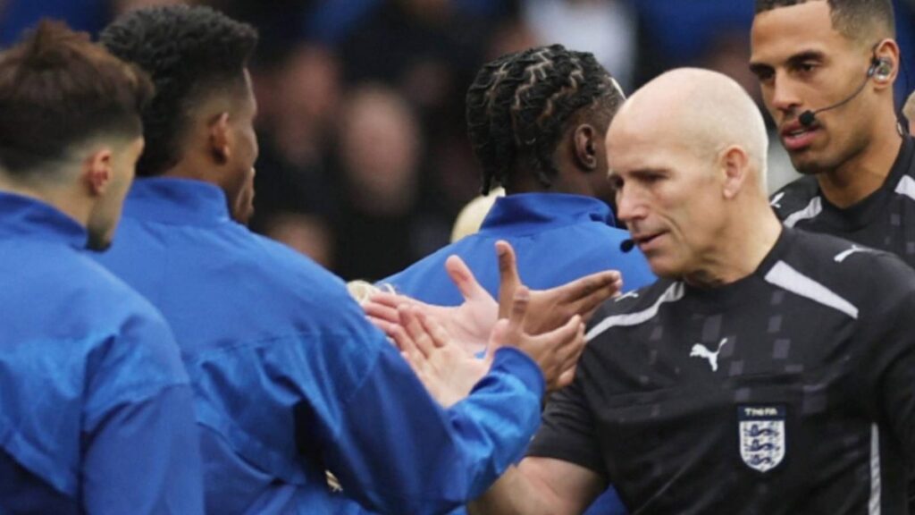 Assistant referee Richard West holding a flag on the touchline during a Premier League football match