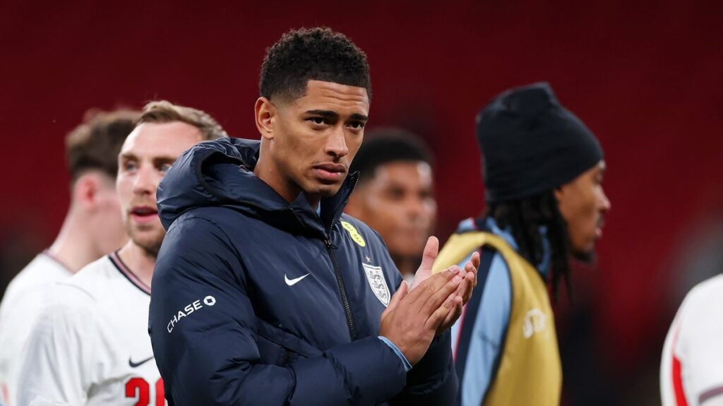 Jude Bellingham sitting on the England substitutes bench looking frustrated during an international friendly match