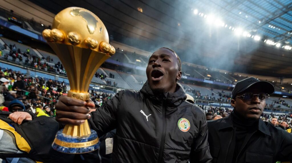 Senegal players celebrating on the pitch with the Africa Cup of Nations trophy