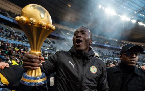 Senegal players celebrating on the pitch with the Africa Cup of Nations trophy