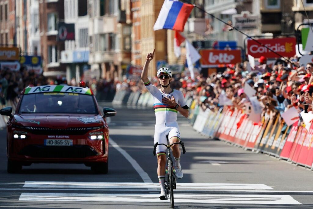 Tadej Pogacar pointing to the sky while crossing the finish line at Liege-Bastogne-Liege to honour a late teammate.