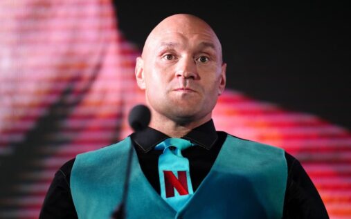 Tyson Fury standing in a boxing ring addressing the media and crowd