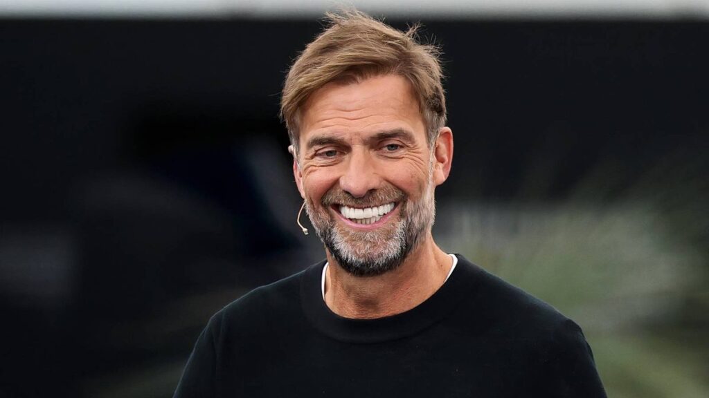 Jurgen Klopp smiling while standing on the touchline at Anfield