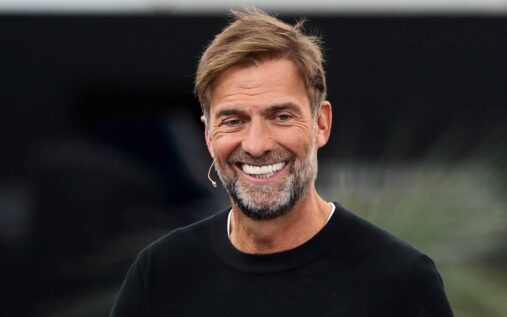 Jurgen Klopp smiling while standing on the touchline at Anfield