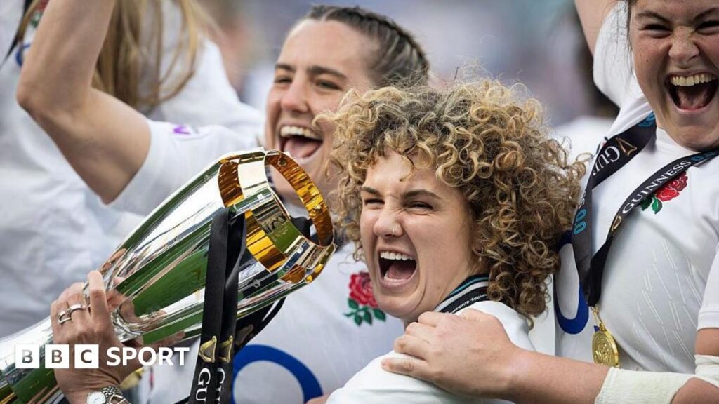 England women's rugby players celebrating in front of a packed stadium of supporters