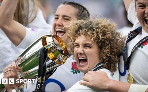 England women's rugby players celebrating in front of a packed stadium of supporters