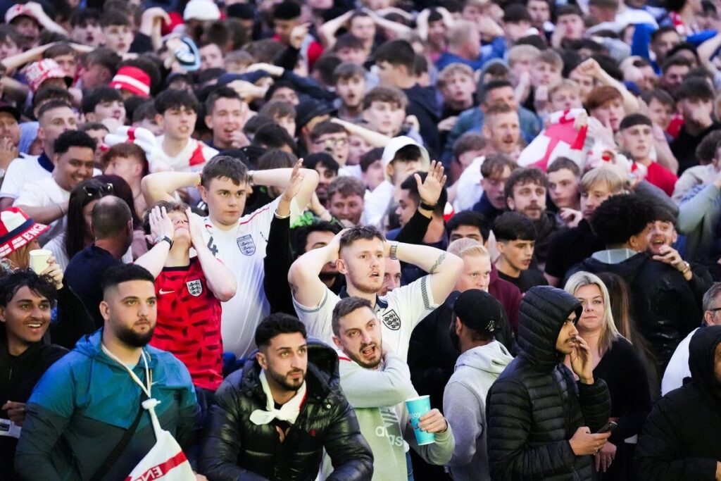 Football supporters walking towards a stadium wearing international team colours