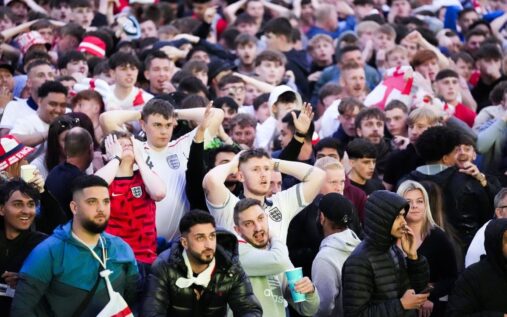 Football supporters walking towards a stadium wearing international team colours