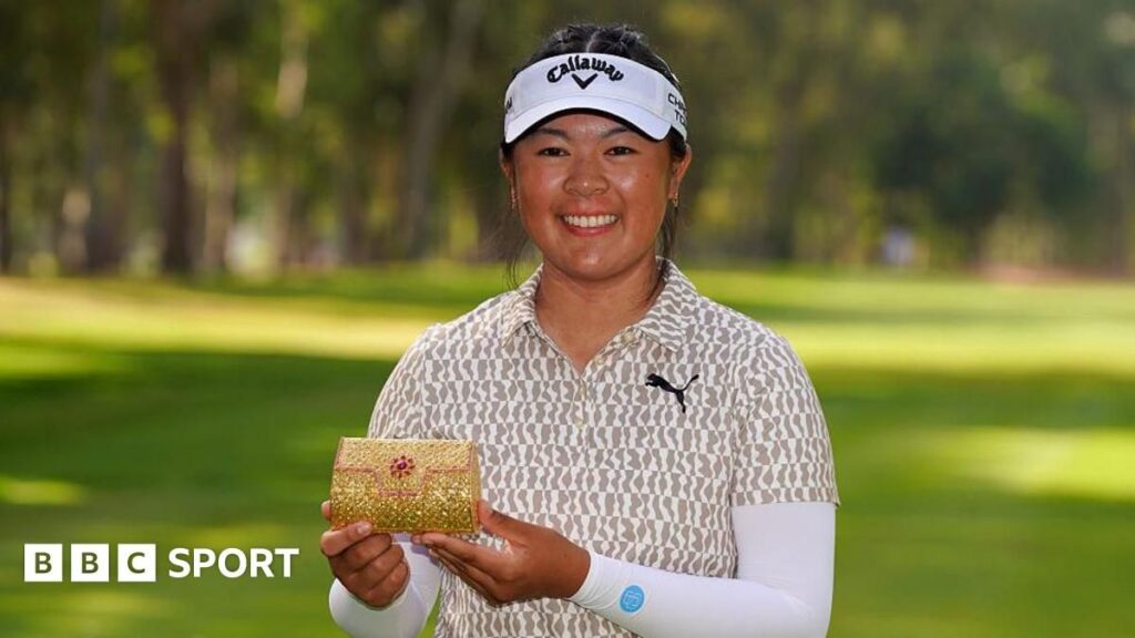 Anna Huang smiling and holding the Lalla Meryem Cup trophy on the golf course in Morocco