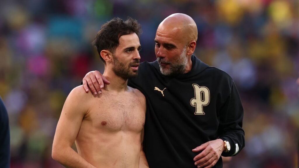 Bernardo Silva and Pep Guardiola talking on the touchline during a Manchester City match