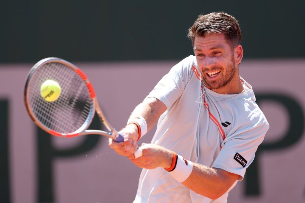 Cameron Norrie walking off a clay court looking dejected after retiring from the French Open