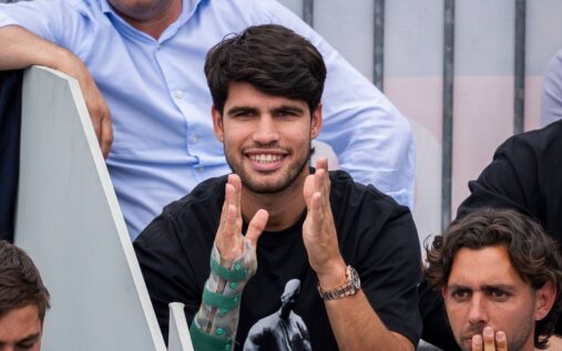 Carlos Alcaraz looking disappointed on a tennis court with a strapped wrist