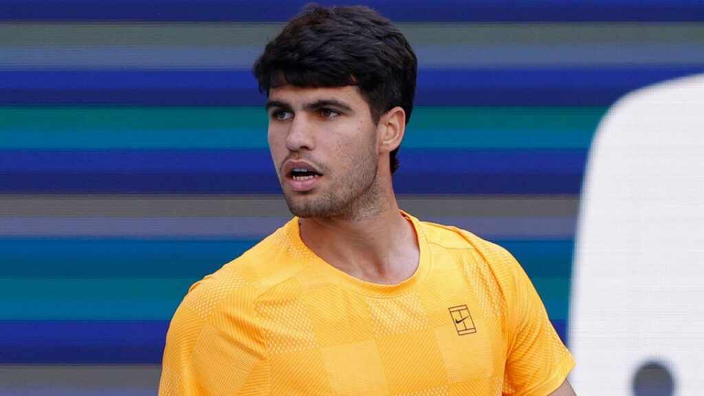 Carlos Alcaraz looking dejected on a tennis court holding his tennis racket