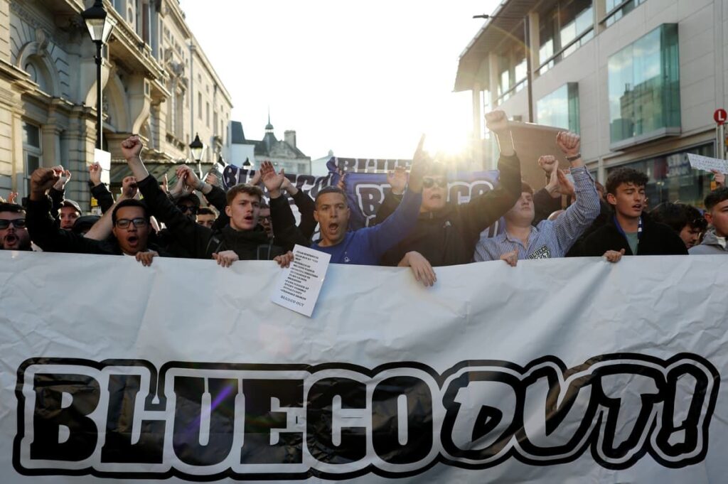 Chelsea supporters holding protest banners against BlueCo ownership outside a football stadium