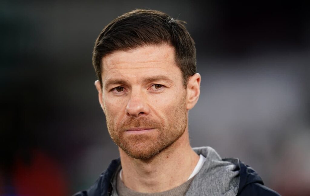 Xabi Alonso standing on the touchline in a suit directing his team during a match
