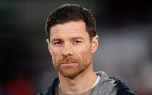 Xabi Alonso standing on the touchline in a suit directing his team during a match