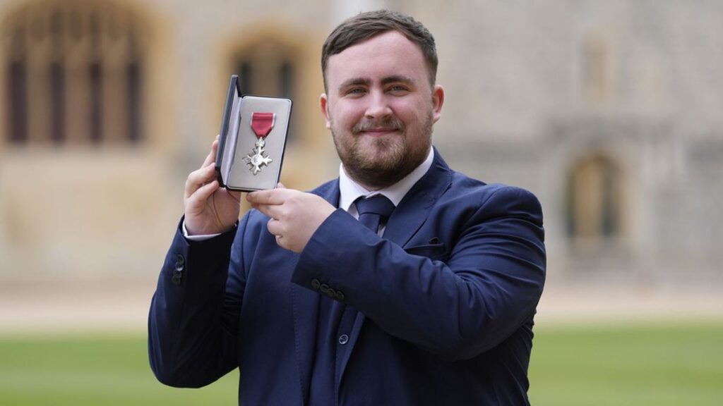 Luke Littler smiling as he is presented with his MBE medal by Prince William at Windsor