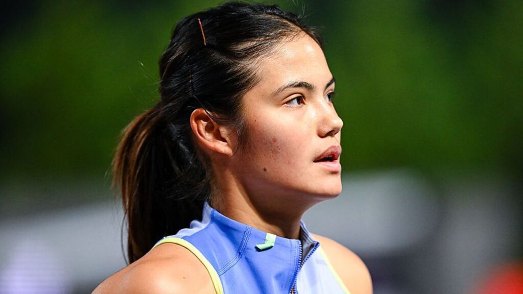 Emma Raducanu holding her tennis racket and looking disappointed on a clay court