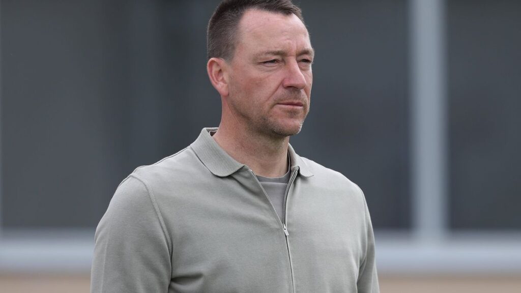John Terry looking serious while Arsenal players celebrate in the background