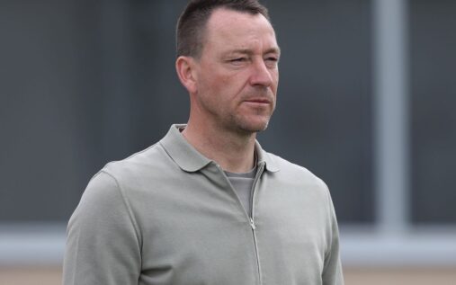 John Terry looking serious while Arsenal players celebrate in the background