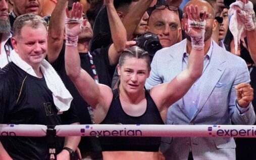 Katie Taylor holding her championship boxing belts after a victory in the ring