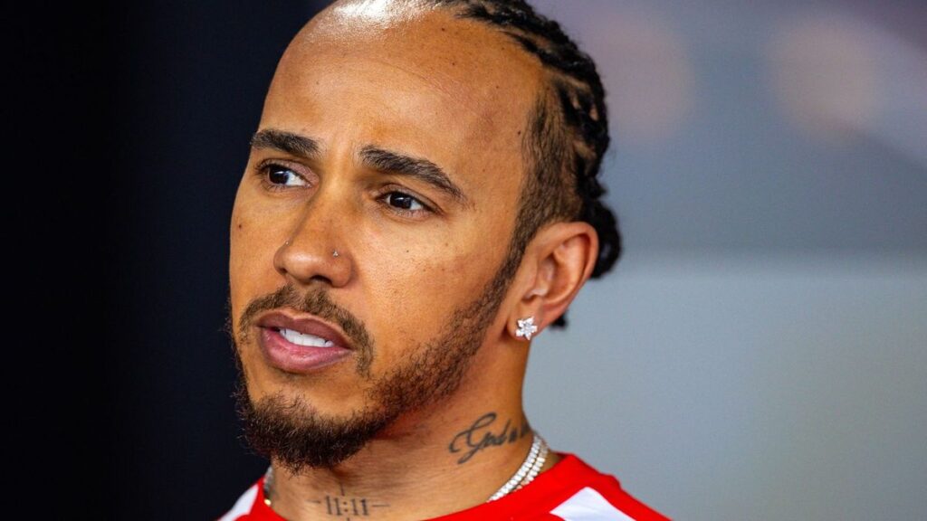 Lewis Hamilton wearing his Ferrari team racewear looking focused in the Formula 1 paddock
