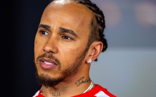 Lewis Hamilton wearing his Ferrari team racewear looking focused in the Formula 1 paddock