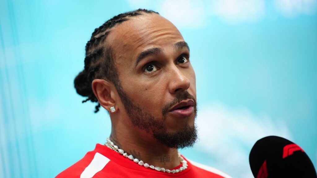 Lewis Hamilton looking thoughtful in his red Ferrari race suit in the Formula 1 paddock