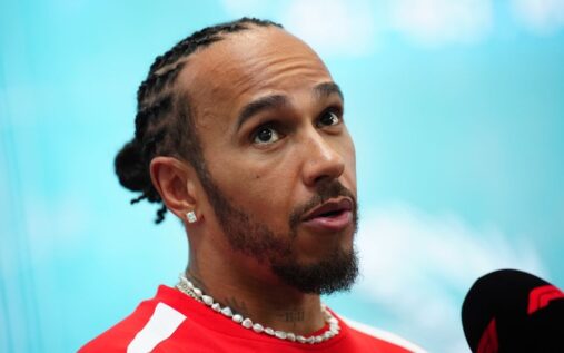 Lewis Hamilton looking thoughtful in his red Ferrari race suit in the Formula 1 paddock