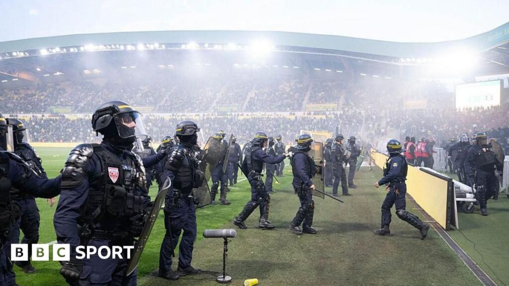 Hooded Nantes supporters throwing flares and invading the pitch at the Stade de la Beaujoire