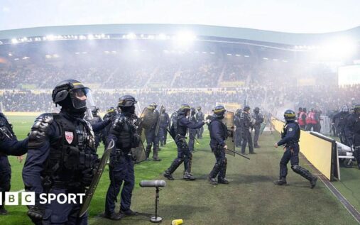 Hooded Nantes supporters throwing flares and invading the pitch at the Stade de la Beaujoire
