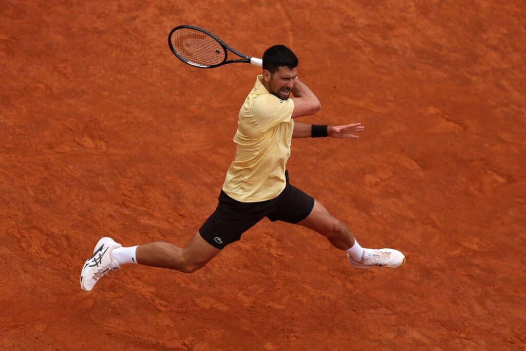 Novak Djokovic preparing to hit a forehand during a clay-court tennis match at the French Open