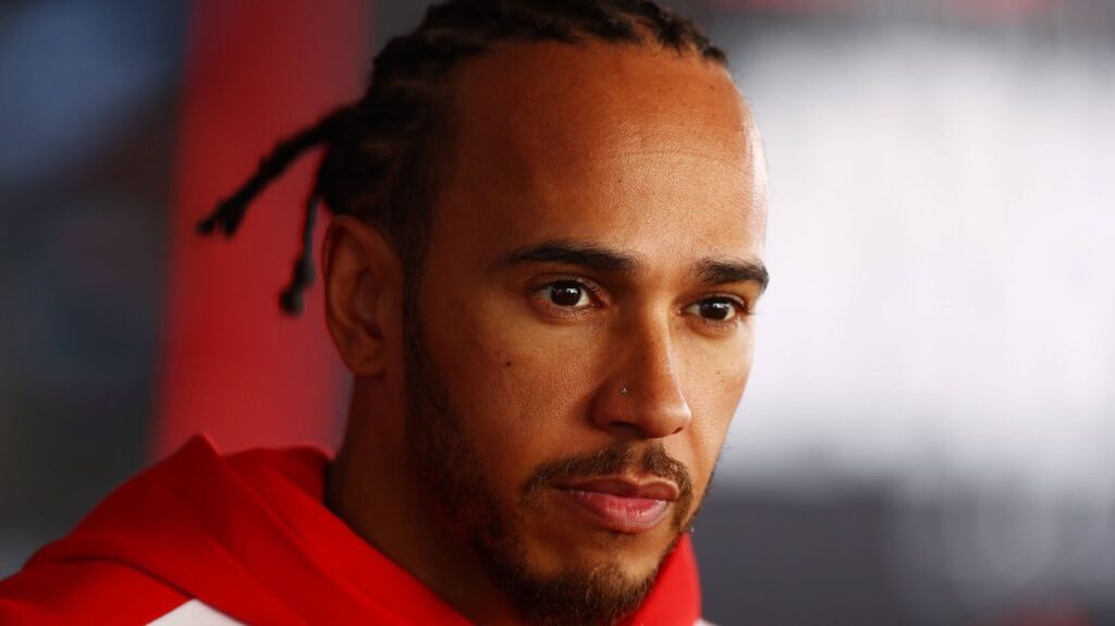 Lewis Hamilton walking through the paddock in his Ferrari race suit