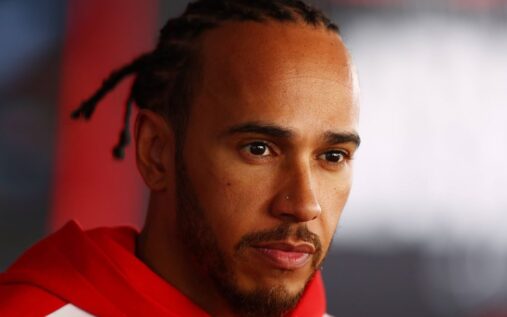 Lewis Hamilton walking through the paddock in his Ferrari race suit
