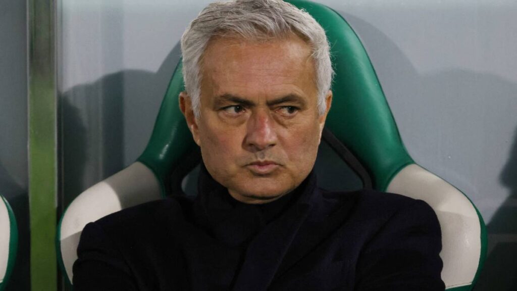 Jose Mourinho standing on the touchline wearing a dark coat while directing his team