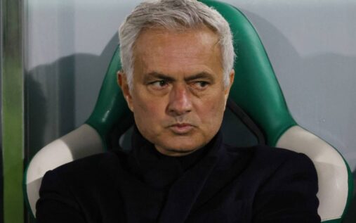 Jose Mourinho standing on the touchline wearing a dark coat while directing his team
