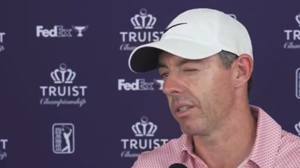 Rory McIlroy smiling on the golf course while wearing his tournament attire