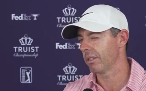 Rory McIlroy smiling on the golf course while wearing his tournament attire