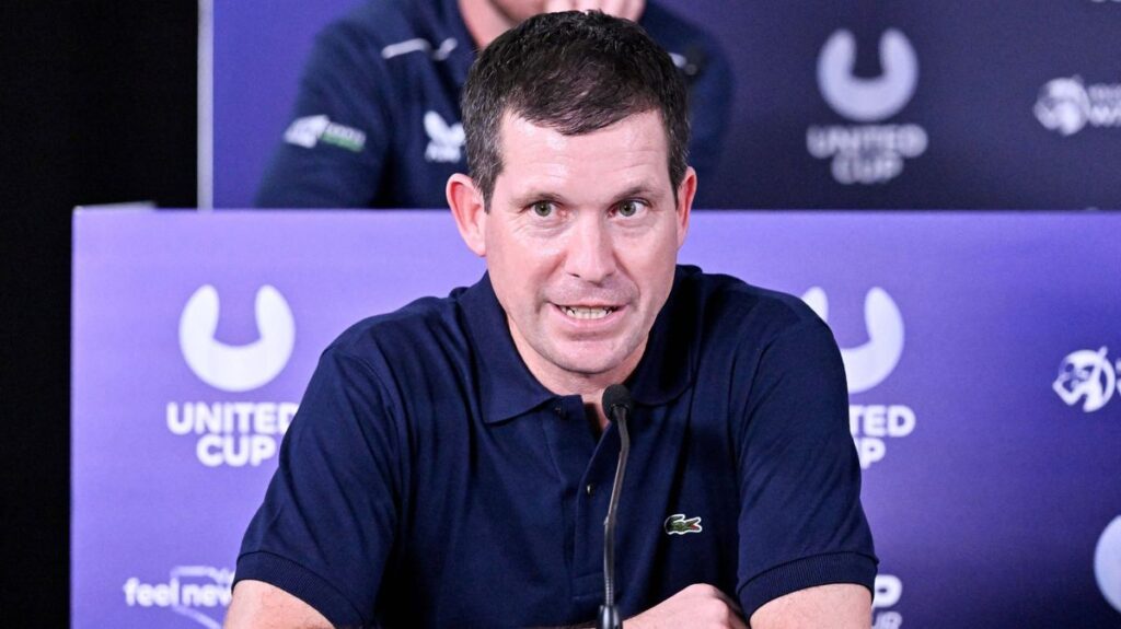 Tim Henman looking serious while watching a tennis match from the stands at Wimbledon