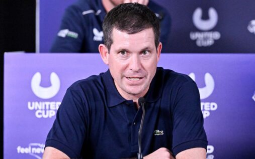 Tim Henman looking serious while watching a tennis match from the stands at Wimbledon