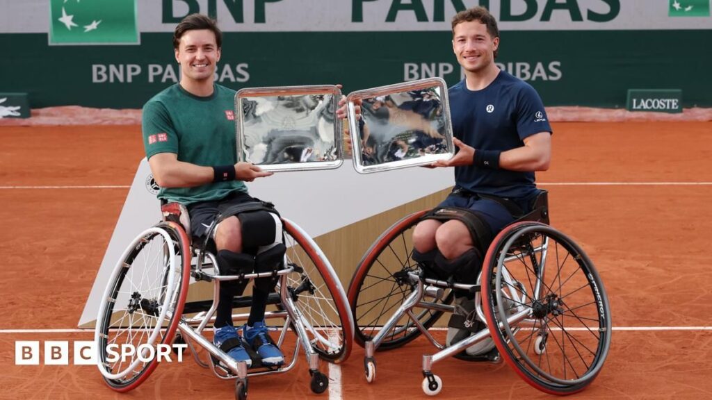 Alfie Hewett and Gordon Reid holding their French Open wheelchair doubles championship trophies on a clay court