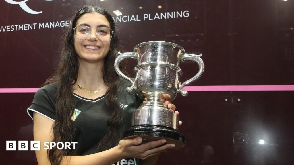 Amina Orfi holding the British Open squash trophy and celebrating her historic victory