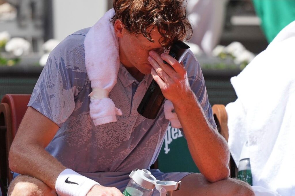Jannik Sinner looking physically exhausted on a clay court during his French Open match