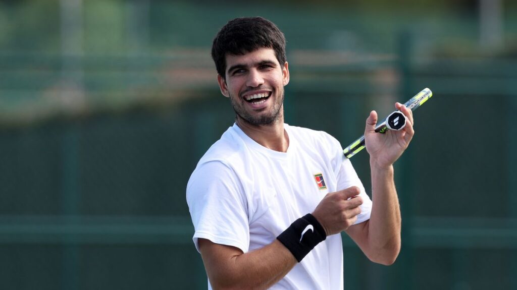 Carlos Alcaraz looking dejected on a tennis court holding his tennis racquet