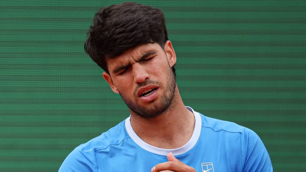 Carlos Alcaraz walking off a tennis court looking dejected after withdrawing from a tournament