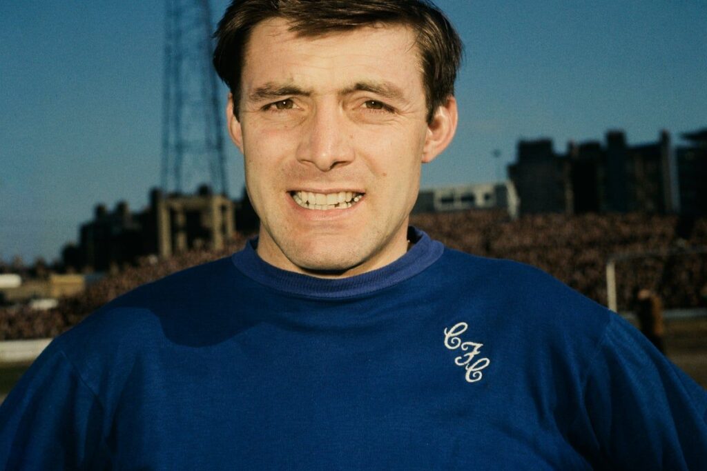 Bobby Tambling smiling in a retro blue Chelsea football kit during his playing career