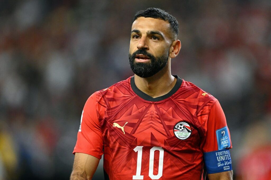 Mohamed Salah sitting on the substitutes bench with an ice pack on his left knee